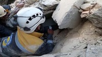 Tim SAR harus menjulurkan tangan melalui celah reruntuhan untuk menjangkau korban. Reuters/White Helmets.