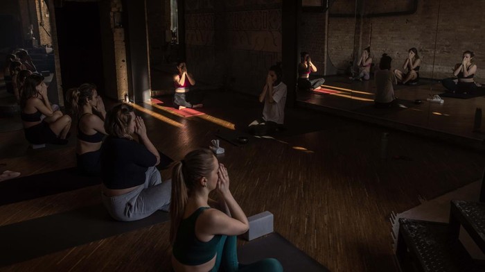 Cara Wanita Ukraina Tenangkan Pikiran di Tengah Perang KYIV, UKRAINE - FEBRUARY 08: Women attend a yoga class in a studio on February 8, 2023 in downtown Kyiv, Ukraine. February 24 will mark one year since Russia's large-scale invasion of Ukraine. In the time since, fighting has largely concentrated in the east and south of the country, but the capital remains the target of regular air strikes. (Photo by Roman Pilipey/Getty Images)