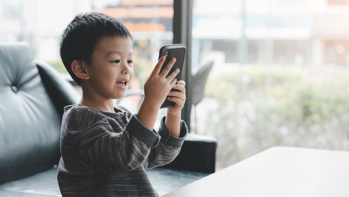 baby cute boy playing games on a tablet or smartphone and watching cartoons.