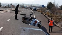 Warga melihat mobil yang terperosok ke lubang.