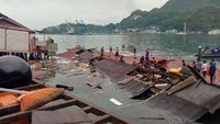 Sejumlah warga berdiri di atap toko yang roboh di pelabuhan setelah diguncang gempa berkekuatan M 5,2 di Jayapura, Papua, Kamis (9/2/2023).