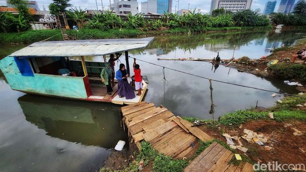 Warga memanfaatkan perahu eretan yang melintas di Sungai Banjir Kanal Barat, Jakarta Barat, Kamis (9/2/2023). Perahu eretan ini menghubungkan Kota Bambu Utara, Jakbar dengan kawasan Cideng, Jakarta Pusat. Sekali tempuh, pengguna membayar Rp 2.000. Perahu eretan memangkas jarak jika harus melewati jembatan besi yang jumlahnya tak banyak.