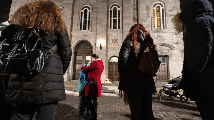 Penampakan Bus yang Tabrak Pusat Penitipan Anak di Kanada A person lights a candle during a vigil outside a church close to the site where a Laval city bus crashed into the daycare, in Laval, Quebec, Canada February 8, 2023. REUTERS/Christinne Muschi