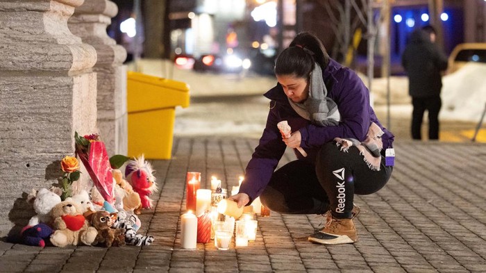 A person lights a candle during a vigil outside a church close to the site where a Laval city bus crashed into the daycare, in Laval, Quebec, Canada February 8, 2023. REUTERS/Christinne Muschi
