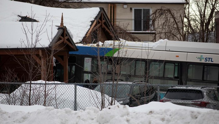 Penampakan Bus yang Tabrak Pusat Penitipan Anak di Kanada A person lights a candle during a vigil outside a church close to the site where a Laval city bus crashed into the daycare, in Laval, Quebec, Canada February 8, 2023. REUTERS/Christinne Muschi