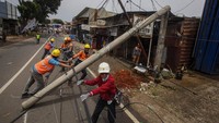 Sejumlah petugas mengevakuasi tianglistrik yang roboh di Jalan Raya Kalimulya,Cilodong, Depok, Jawa Barat, Kamis(9/2/2023).