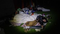 Warga tidur di tempat perlindungan sementara yang didirikan di lapangan sepak bola di Hatay, Turki.   