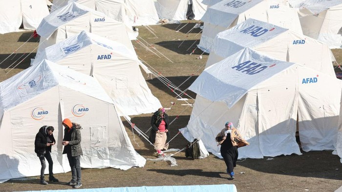 People walk next to tents at a camp set up by the government at Kahramanmaras Stadium, in the south of Turkey,on February 8, 2023. - Rescuers in Turkey and Syria braved frigid weather, aftershocks and collapsing buildings, as they dug for survivors buried by an earthquake that killed more than 5,000 people. Some of the heaviest devastation occurred near the quake's epicentre between Kahramanmaras and Gaziantep, a city of two million where entire blocks now lie in ruins under gathering snow. (Photo by Adem ALTAN / AFP) (Photo by ADEM ALTAN/AFP via Getty Images)