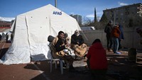Orang-orang menghangatkan diri di sekitar api di luar tenda di sebuah kamp yang didirikan oleh pemerintah di kota Kahramanmaras, Turki tenggara. Korban gempa menghadapi cuaca dingin dan gempa susulan. Ozan Kose/AFP/Getty Images  
