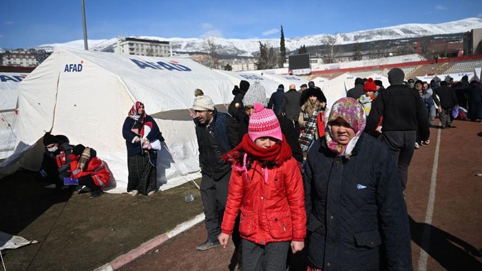 Families walk past tents at a camp set up by the government in the southeastern Turkish city of Kahramanmaras, two days after a strong earthquake struck the region, on February 8, 2023. - Many have taken refuge from relentless aftershocks, cold rain and snow in mosques, schools and even bus shelters -- burning debris to try to stay warm, after the earthquake, which is the largest Turkey had seen since 1939. (Photo by OZAN KOSE / AFP) (Photo by OZAN KOSE/AFP via Getty Images)