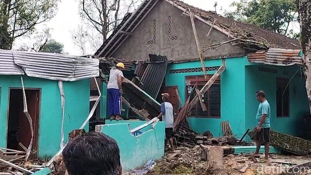 Warga memotongi batang pohon yang tumbang menimpa rumah warga di Desa Kebongulo, Kecamatan Musuk, Boyolali, Kamis (9/2/2023).
