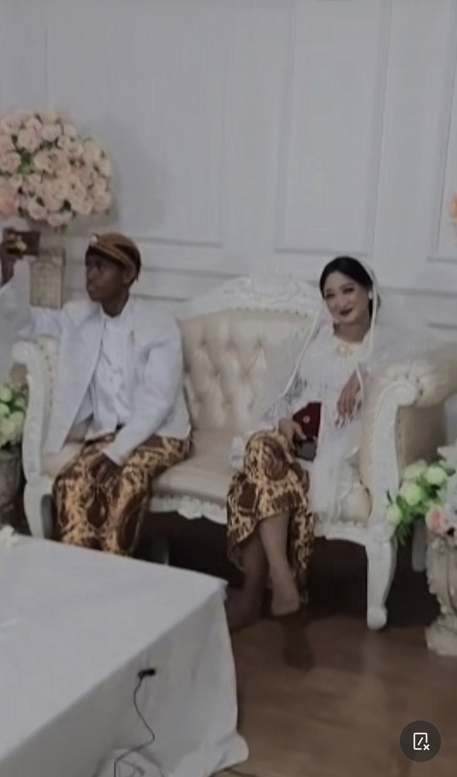 Momen pasangan pengantin berpose di pelaminan ini viral di media sosial. Pasangan tersebut viral karena warganet salfok dengan pengantin pria yang berkulit gelap sementara si wanita berkulit putih. Keduanya disebut bukti cinta tak pandang fisik. Foto: Dok. TikTok @arumpps.