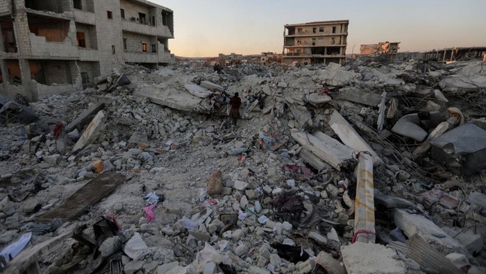 Potret Hatay dan Jandaris Terkini People walk past damaged buildings, in the aftermath of an earthquake, in rebel-held town of Jandaris, Syria February 9, 2023. REUTERS/Khalil Ashawi