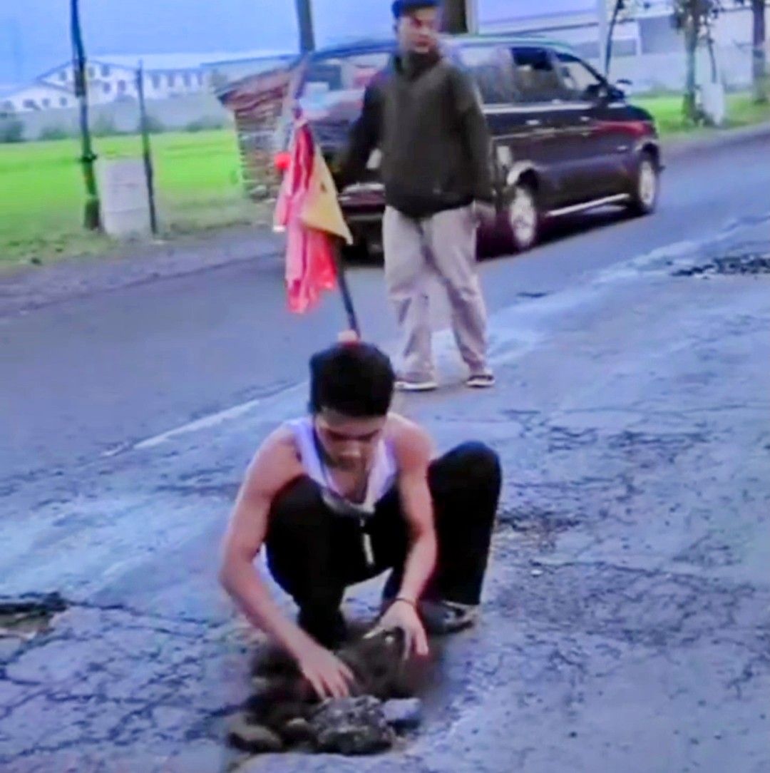 remaja menambal jalan di jalur pantura