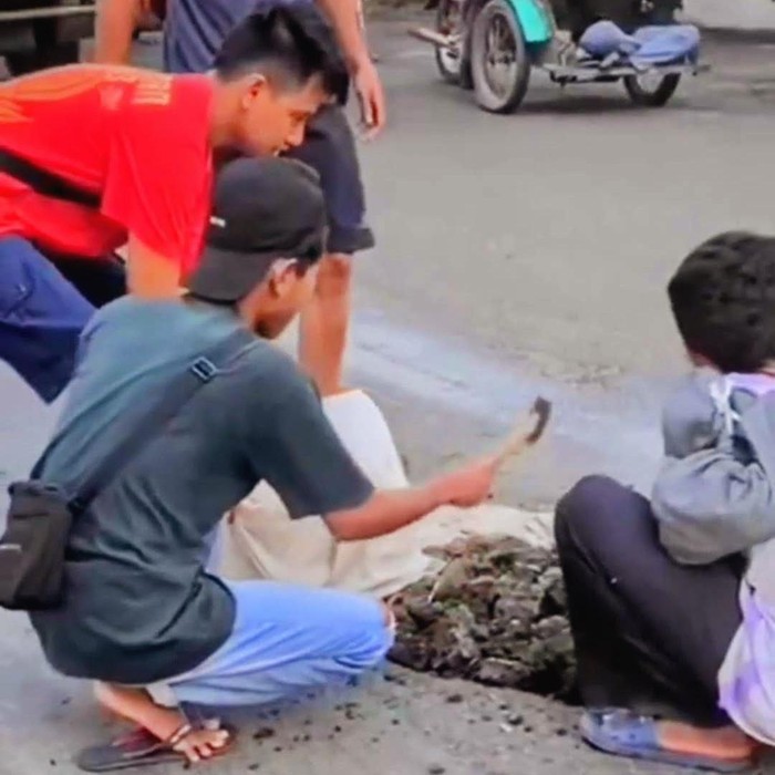 remaja menambal jalan di jalur pantura