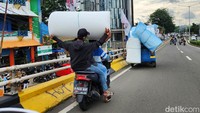 Pengendara motor juga mengambil muatan yang jatuh untuk dikembalikan ke pengemudi bajaj.