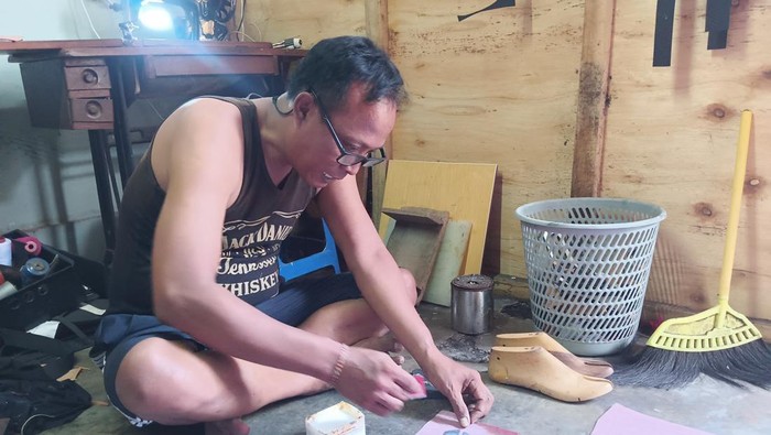 Agung Sudiana tengah membuat upper atau bagian penutup sandal.