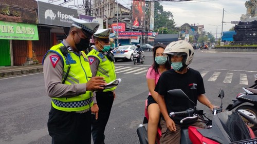 Petugas Satlantas Polres Tabanan memberikan teguran kepada salah seorang pengendara motor yang kedapatan melanggar di simpang Wisnu Murti. (Istimewa)