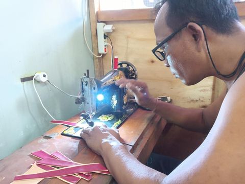 Agung Sudiana mengerjakan pembuatan sandal di bengkel produksinya.
