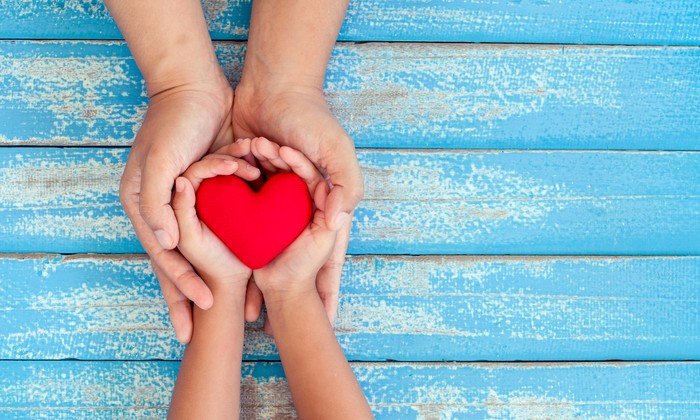 Cute asian little child girl showing and holding red heart in hand with care and love