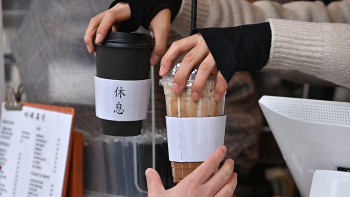 Kopi Americano yang Begitu Digemari Warga Korea Selatan This picture taken on January 26, 2023 shows people holding iced Americanos during an interview with AFP on a street in Seoul. - K-pop stars BTS drink it. It appears in K-dramas. Fans are so dedicated to consuming it year-round they've coined a new South Korean proverb: