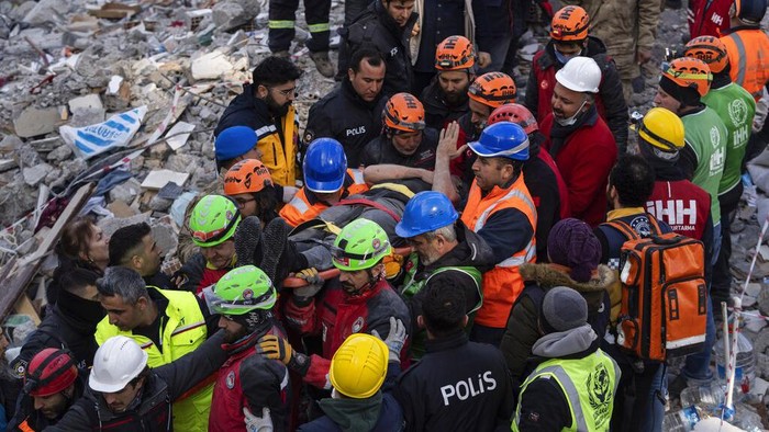 Penyelamatan Suami Istri Setelah 109 Jam Tertimbun Reruntuhan Gempa Haci Murat Kilinc is carried through a crowd on a stretcher after he was rescued under a destroyed building in Iskenderun, southeastern Turkey, Friday, Feb. 10, 2023. A married couple was pulled from beneath the rubble of a collapsed building in Iskenderun after spending 109 hours buried within a small crevice. (AP Photo/Petros Giannakouris)