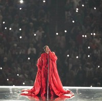 Sebuah coat merah bervolume dramatis juga terlihat menemani gayanya. Banyak fans menyebut outerwear tersebut merupakan bentuk penghormatan Rihanna bagi mendiang sahabatnya, Andre Leon Talley, editor kulit hitam pertama Vogue yang meninggal tahun lalu. (Foto: AP/Ashley Landis)