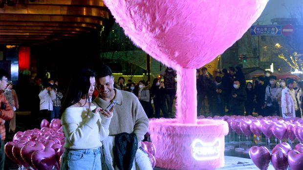 Warga menyaksikan instalasi dekoratif berbentuk hati setinggi 5 meter yang dikelilingi balon berbentuk hati di Bund Finance Center sebelum Hari Valentine pada 12 Februari 2023 di Shanghai, China. (Photo by VCG/VCG via Getty Images)