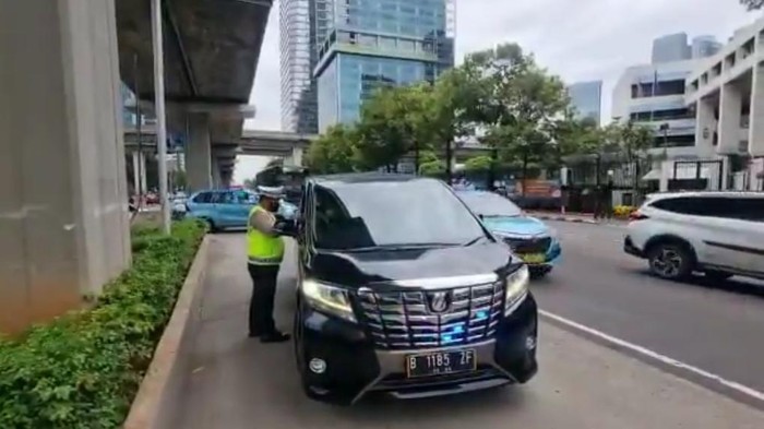 Kendaraan Toyota Vellfire di Jaksel dihentikan polisi karena menggunakan strobo. Polisi menegur dan mencopot strobo di mobil tersebut. (Twitter @TMCPoldaMetro)