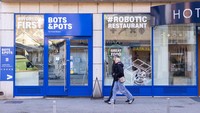Orang-orang berjalan di samping restoran robot Bots & Pots di Zagreb, Kroasia, Kamis (9/2/2023). Pemiliknya mengatakan mereka yakin bistro BOTS&POTS Sci-Food di Zagreb adalah satu-satunya restoran di dunia di mana makanan siap saji dalam panci dibuat oleh robot pemasak tanpa keterlibatan manusia selain memuat perangkat dengan bahan-bahan segar.