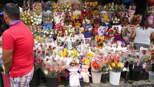 People buy from a flower market along a busy road in Manila, Philippines on Monday, Feb. 13, 2023. Prices of flowers have increased due to the high demand a day before Valentines Day. (AP Photo/Aaron Favila)
