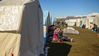 Orang-orang duduk di tenda-tenda yang didirikan di Adiyaman, Turki selatan. Ribuan orang kehilangan tempat tinggal akibat gempa bumi dahsyat yang melanda Turki dan Suriah seminggu yang lalu. AP/Emrah Gurel  