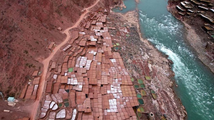 Aktivitas Tambak Garam di China yang Usianya 1.000 Tahun CHANGDU, CHINA - FEBRUARY 13: A villager watches salt pans along the Lancang River on February 13, 2023 in Markam County, Changdu City, Tibet Autonomous Region of China. Villagers in Markam County make salt by evaporating brine in the sun, which has a history of more than 1000 years. (Photo by Li Lin/China News Service/VCG via Getty Images)