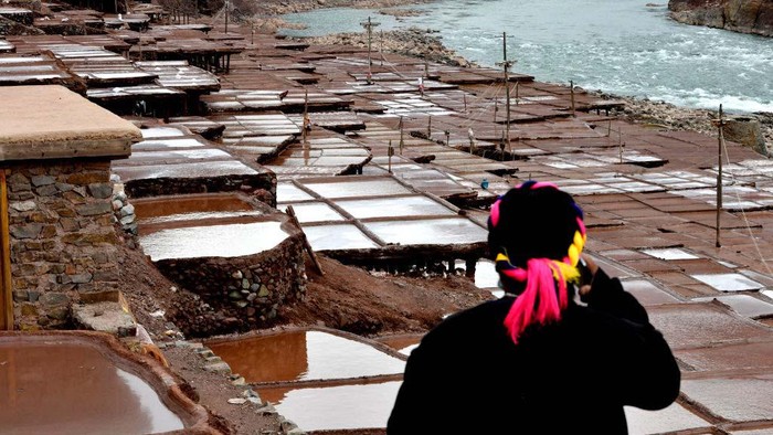 Aktivitas Tambak Garam di China yang Usianya 1.000 Tahun CHANGDU, CHINA - FEBRUARY 13: A villager watches salt pans along the Lancang River on February 13, 2023 in Markam County, Changdu City, Tibet Autonomous Region of China. Villagers in Markam County make salt by evaporating brine in the sun, which has a history of more than 1000 years. (Photo by Li Lin/China News Service/VCG via Getty Images)