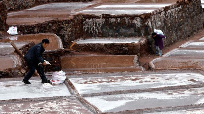 Aktivitas Tambak Garam di China yang Usianya 1.000 Tahun CHANGDU, CHINA - FEBRUARY 13: A villager watches salt pans along the Lancang River on February 13, 2023 in Markam County, Changdu City, Tibet Autonomous Region of China. Villagers in Markam County make salt by evaporating brine in the sun, which has a history of more than 1000 years. (Photo by Li Lin/China News Service/VCG via Getty Images)