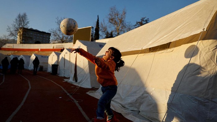 Anak Pengungsi Gempa Turki Asyik Bermain Bola A child receives food inside a stadium in the aftermath of a deadly earthquake in Kahramanmaras, Turkey February 14, 2023. REUTERS/Suhaib Salem