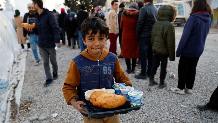 Anak Pengungsi Gempa Turki Asyik Bermain Bola A child receives food inside a stadium in the aftermath of a deadly earthquake in Kahramanmaras, Turkey February 14, 2023. REUTERS/Suhaib Salem