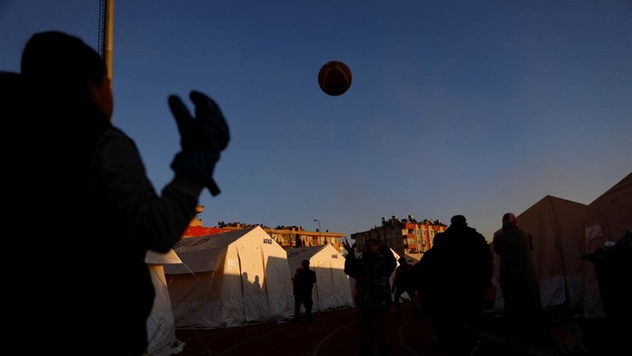 Anak Pengungsi Gempa Turki Asyik Bermain Bola A child receives food inside a stadium in the aftermath of a deadly earthquake in Kahramanmaras, Turkey February 14, 2023. REUTERS/Suhaib Salem