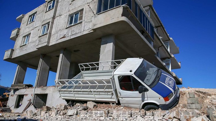 Gempa tidak hanya membuat gedung dan rumah ambruk di Turki. Gempa itu juga merobohkan diler mobil bekas di Gaziantep. Mobil-mobil pun ringsek tak berbentuk.