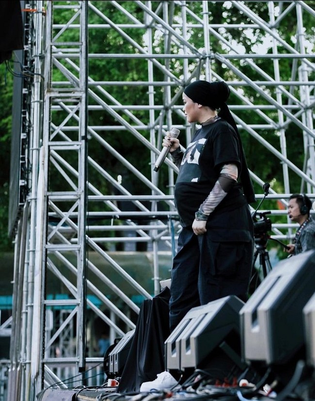 Inilah style hijab boyish yang menjadi ciri khas Sivia Azizah. Dia mengenakan kaus oversized, hijab yang diikat ke belakang dan celana kulot saat manggung. Alhamdullillah ternyata gue tetep bisa ada di atas panggung. Produktif, sekarang lagi produce album 2 doain lancar jg ya xixi. Manggung dalam kondisi hamil gini bener-bener udah liga yang berbeda lagi sih buat gue, gak cuma perbedaan secara fisik ya, tapi secara mental, emosional juga berbeda. Tapi happy sih dan bersyukur bgt karena gue udah di fase ini di dalam hidup gue. #Blesseeedd #GodIsGoooood!!💖🙏🏼🤞🏻 difotoin @pria_hardie yang sambil deg2ser kasih2 kode suruh duduk dan minum 🤣😚@festivalpasarmusik, tulis Sivia.  Foto: Dok. Instagram @siviazizah.