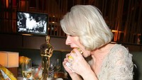 Makan burger ala Helen Mirren nih! Tak semua orang bisa melakukannya karena ia membawa Piala Oscar.