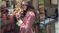 Aktris Dakota Johnson juga pernah pamer momen makan pretzel pakai busana mewah. Ia memakai setelan Gucci di Times Square, New York. 
