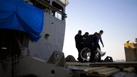 Tampak salah satu pasien yang memakai kursi roda yang dibantu keluar dari kapal.