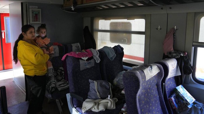 Melihat Korban Gempa Turki yang Tinggal di Gerbong Kereta A man gives supplies to another one who stays inside a train, using as a shelter, in Iskenderun city, southern Turkey, Tuesday, Feb. 14, 2023. Thousands left homeless by a massive earthquake that struck Turkey and Syria a week ago packed into crowded tents or lined up in the streets for hot meals as the desperate search for survivors entered what was likely its last hours. (AP Photo/Hussein Malla)