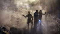Dengan penuh semangat, tim SAR terus melakukan pencarian korban di reruntuan bangunan. Debu yang mengadang pun diterobos. Yavuz Ozden/Getty Images.