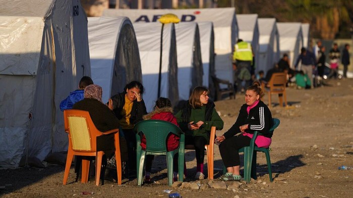 People who lost their houses in the devastating earthquake, lineup to receive food at a makeshift camp, in Iskenderun city, southern Turkey, Tuesday, Feb. 14, 2023. Thousands left homeless by a massive earthquake that struck Turkey and Syria a week ago packed into crowded tents or lined up in the streets for hot meals as the desperate search for survivors entered what was likely its last hours. (AP Photo/Hussein Malla)