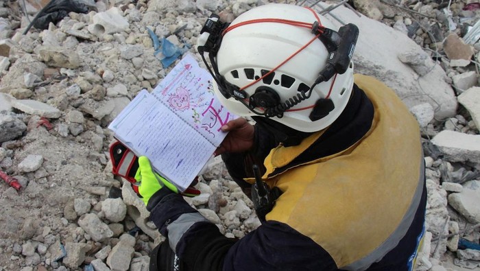 Potret Pilu Buku Harian Anak-anak Korban Gempa di Suriah A White Helmets member looks at a notebook found at a damaged building, in the aftermath of an earthquake, in rebel-held town of Jandaris, Syria, February 10, 2023. White Helmets/Handout via REUTERS THIS IMAGE HAS BEEN SUPPLIED BY A THIRD PARTY. NO RESALES. NO ARCHIVES. MANDATORY CREDIT. TPX IMAGES OF THE DAY