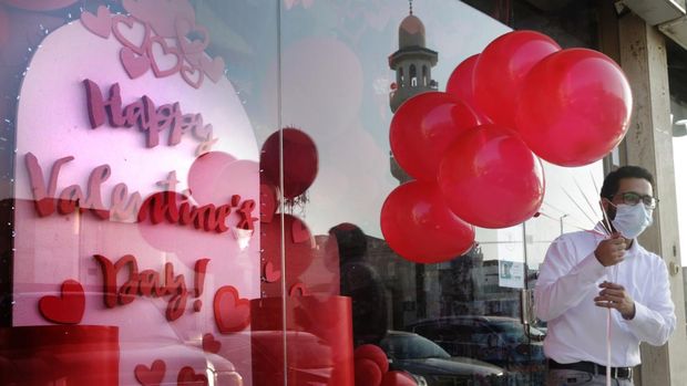 Seorang pria Saudi yang mengenakan topeng untuk melindungi diri dari virus corona memegang balon pada Hari Valentine di luar toko suvenir di Jeddah, Arab Saudi, Minggu, 14 Februari 2021. (File Foto - AP Photo/Amr Nabil)