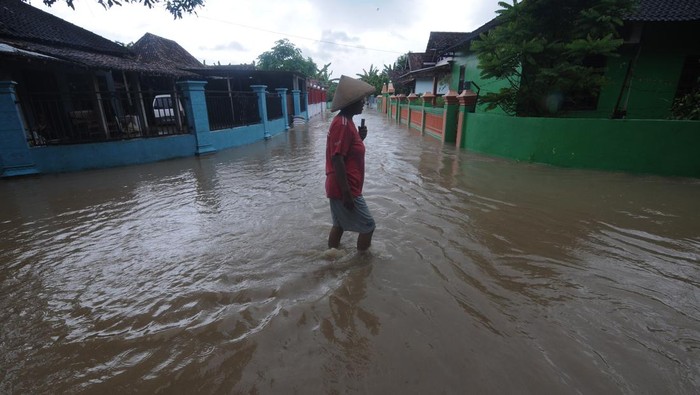 Seorang warga melintas di jalan perkampungan yang terendam banjir di Planggu, Trucuk, Klaten, Jawa Tengah, Rabu (15/2/2023). Intensitas hijan deras menyebabkan aliran sungai Dengkeng meluap dan membanjiri pemukiman warga disekitarnya. ANTARA FOTO/Aloysius Jarot Nugroho/hp.