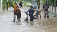 Sejumlah warga melintas di jalan perkampungan yang terendam banjir di Planggu, Trucuk, Klaten, Jawa Tengah, Rabu (15/2/2023).   